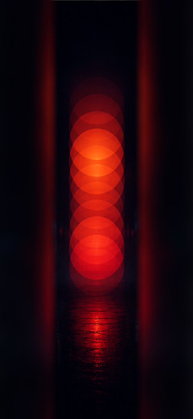 Abstract vertical stack of overlapping glowing red-orange circles on a black background, reflected on dark stone